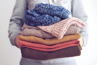 Woman holding stack of sweaters