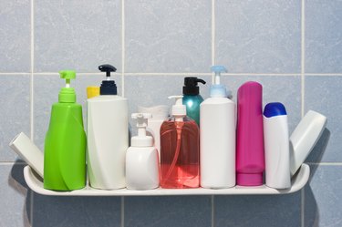 Many shampoo and soap bottles on a bathroom shelf