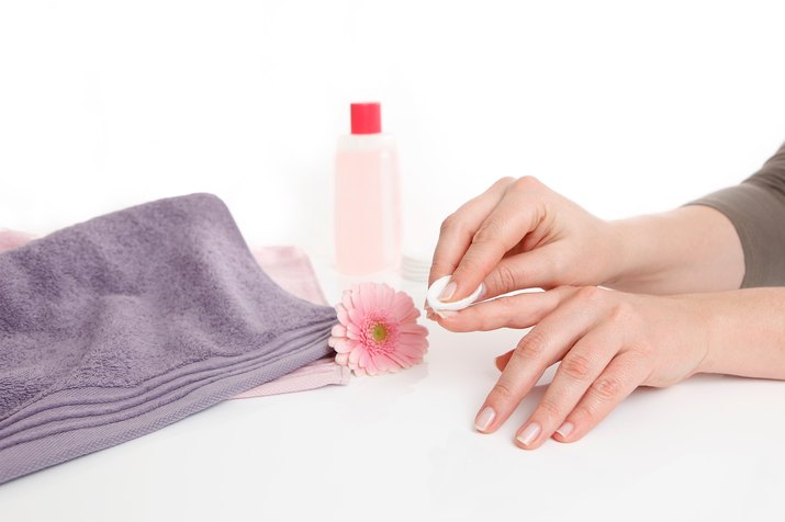 Cropped Hands Of Woman Removing Nail Polish Against White Background