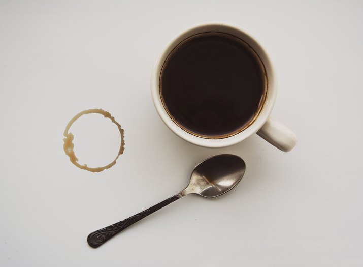 Stain from a cup of coffee, black coffee and a little spoon, white background