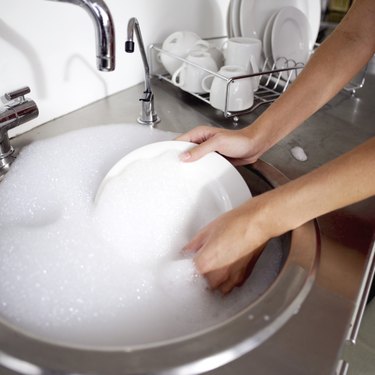 woman washing a plate in the kitchen sink