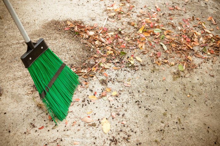 Sweeping dry leaves with broom.Autumn, fall season.Sweep the leaves, sweep people, clean the garden.Maintenance worker in park garden cleans the roads with plastic garden broom .Copy space