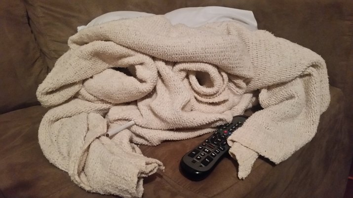 Close-Up Of Knitted Blanket With Remote On Sofa