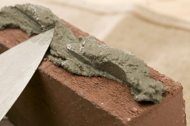 Close-up of brick spread with mortar by spade