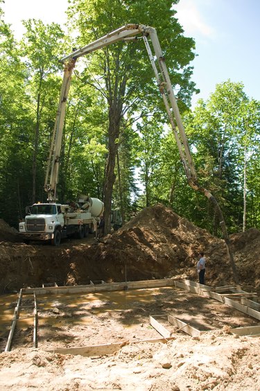 Concrete pump truck pouring foundation at construction site