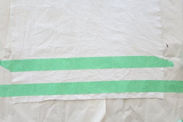 Form a stripe by covering canvas with painter\'s tape.