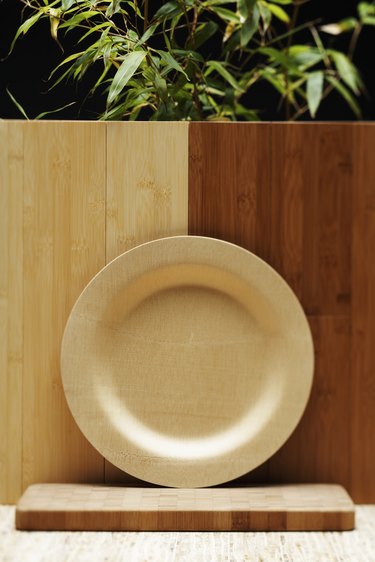 Bamboo plate, cutting board and flooring beside bamboo plant