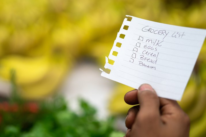 Man Hands Holding Shopping List in a Supermarket