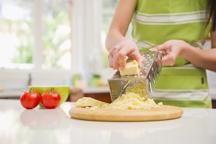 Hispanic woman grating cheese in domestic kitchen