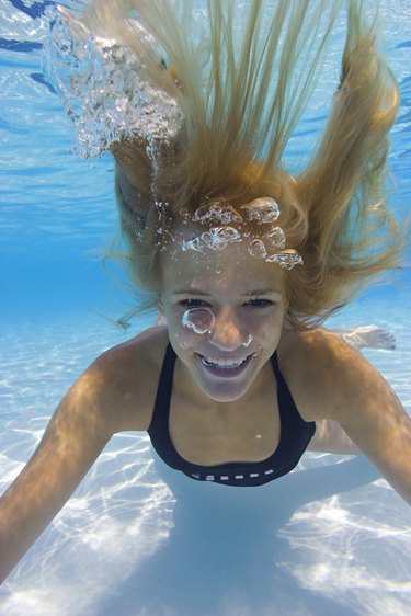 underwater photo of a teenage female as she playfully swims through the water