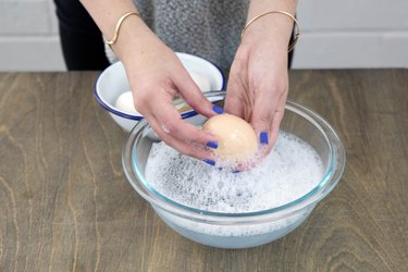 Washing eggs in bowl of warm soapy water.