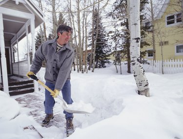 Man shovelling snow from walkway outside house