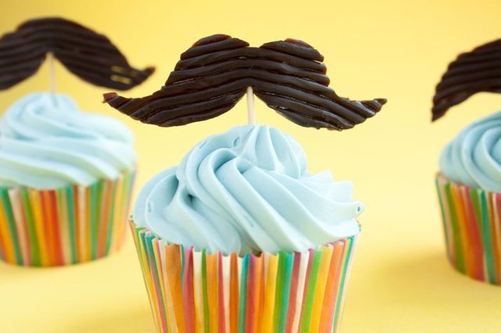 cupcakes with blue frosting and mustache toppers