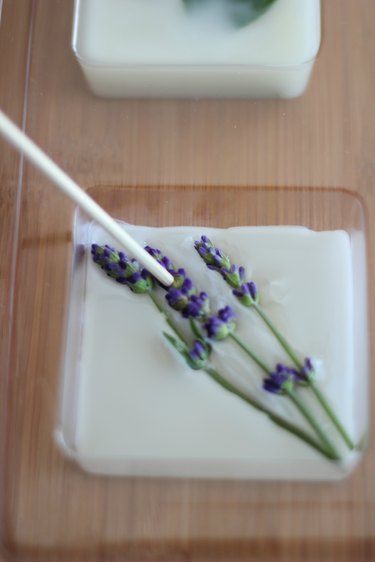 Pour wax over flowers and gently press flowers into wax with a wooden skewe