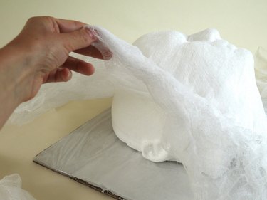 Hand removing the form from under the cheesecloth.