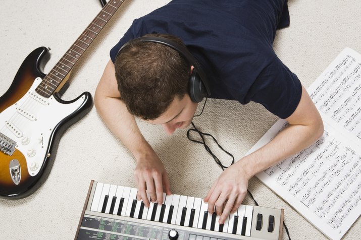 Man playing piano keyboard with headphones