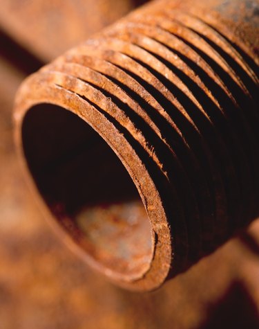 a close-up of a rusted steel pipe lying on other rusted steel pipes